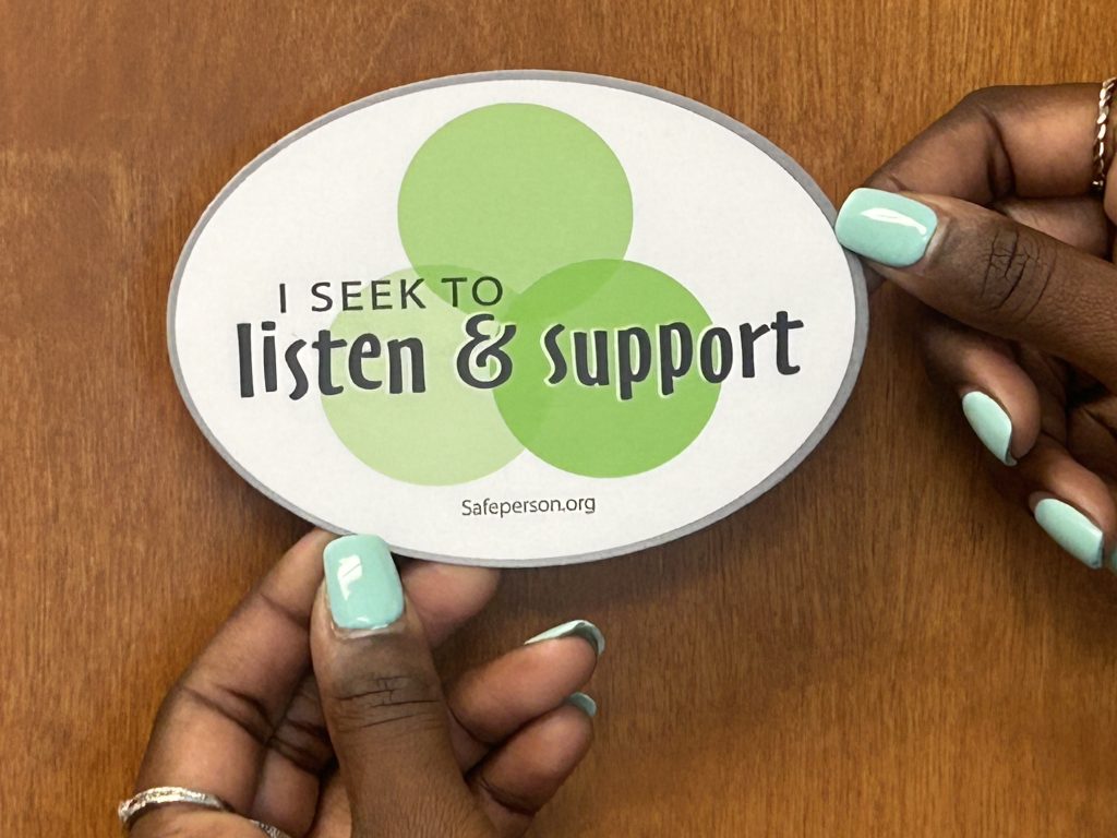 A woman holding the safe person 7 Promises decal.